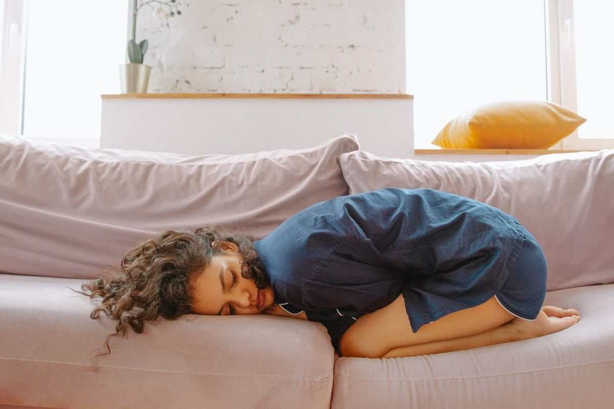 Person lying down on a sofa because of Fatigue due to PMS, hormonal imbalance, PCOD, PCOS, PMOS